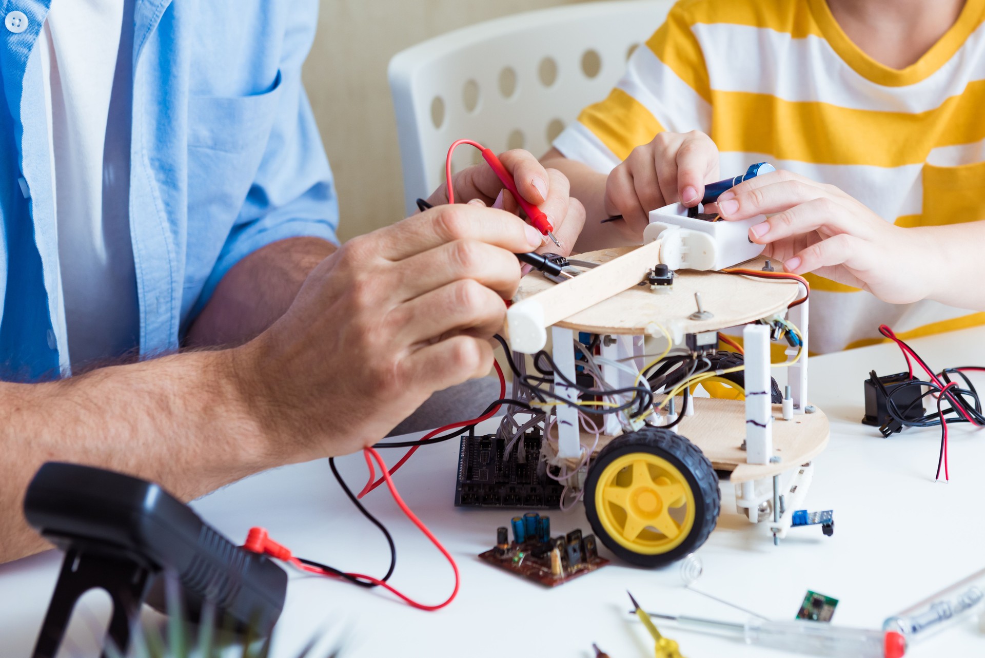 Close up of construction workflow of electronic mechanism with microcontroller at junior robotics club. Collective work creation of diy electronics, modern technologies, innovation and science concept